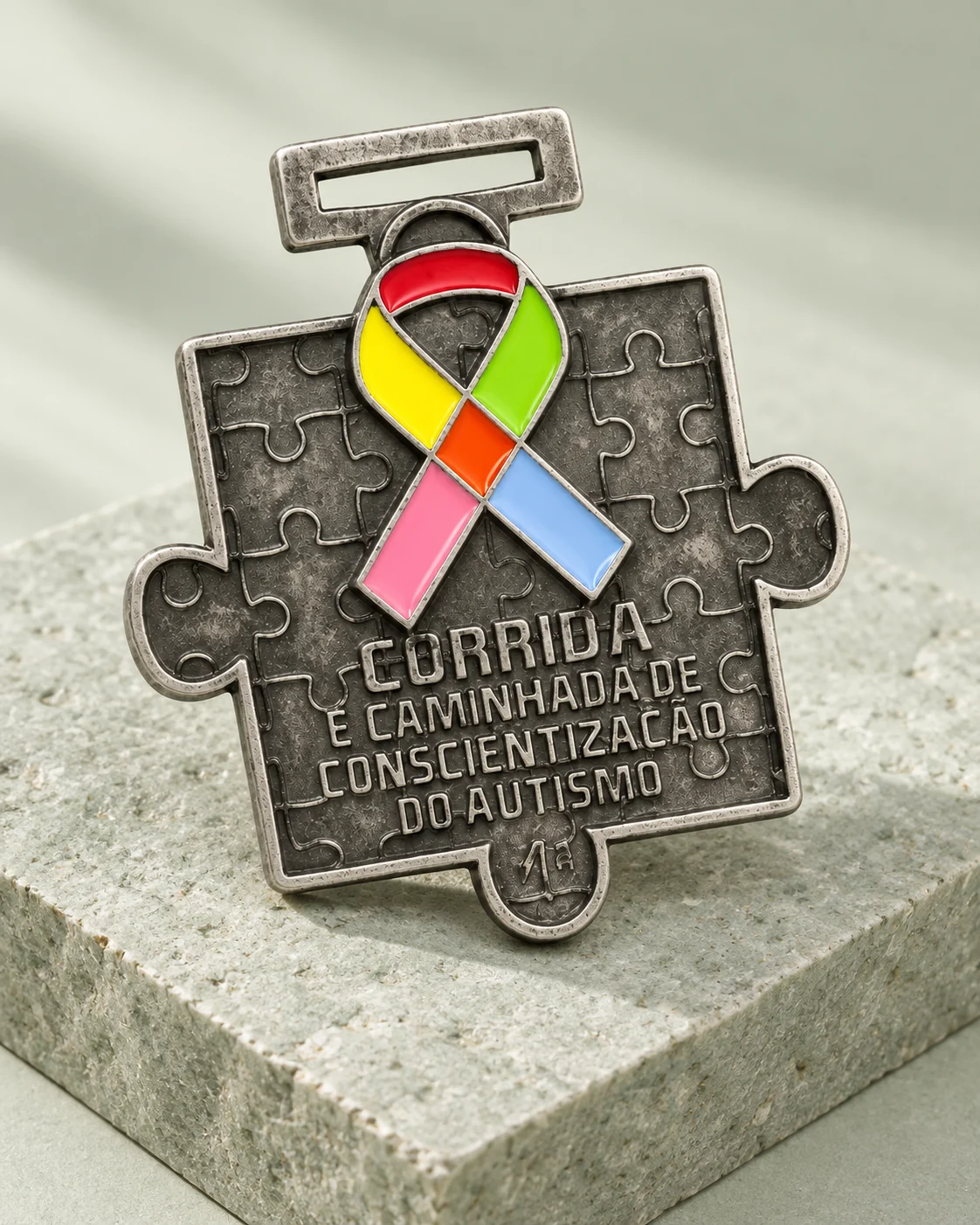Medalha em formato de quebra-cabeça com laço colorido em composição iluminada sobre pedra