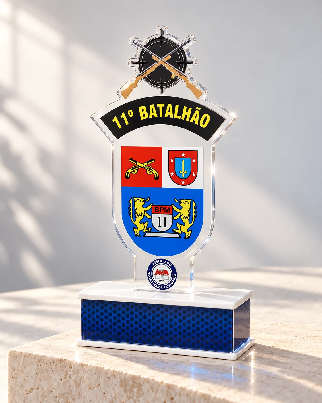 Troféu personalizado do 11º Batalhão sobre pedestal claro, com reflexos no acrílico